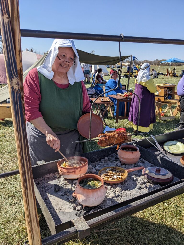 Village woman in historic garb cooks historic food at Bluffwoods Renaissance Festival