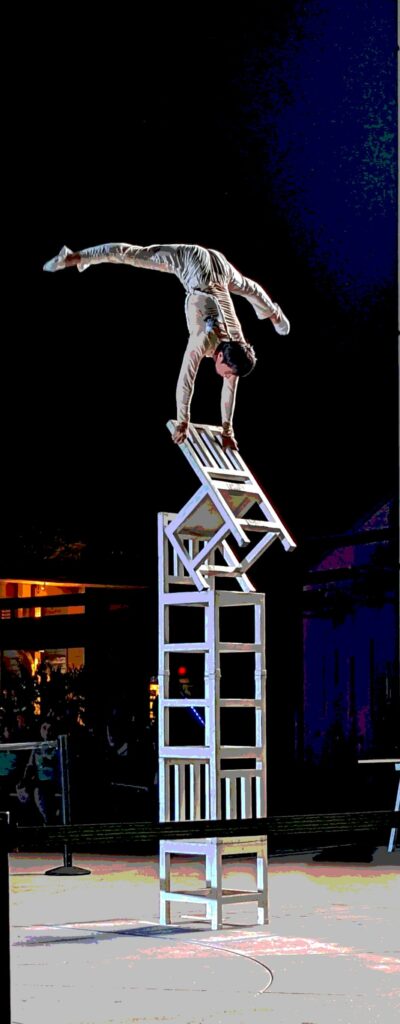 A Chinese Acrobat does a handstand on a precariously balanced stack of chairs at the GloWild Lantern Festival at the Kansas City Zoo