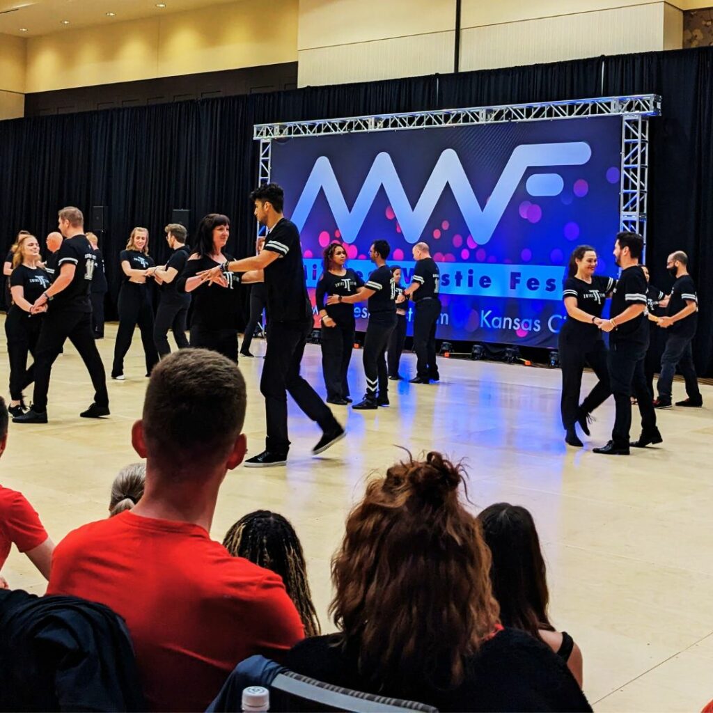 JT Swing Team Performing many couples in matching black and white clothing dance West Coast Swing