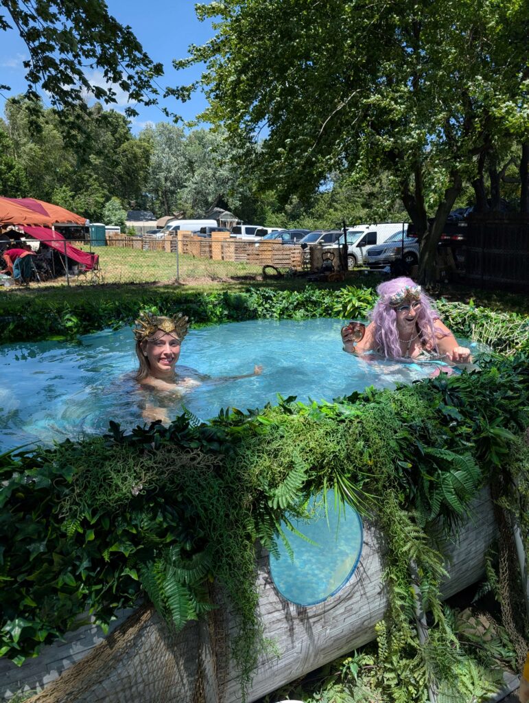 To Mermaids relax in blue waters in an above ground pool at the Topeka Renaissance Festival.