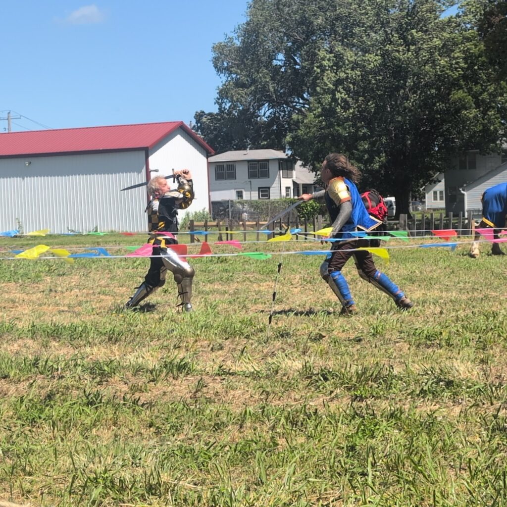 To knights fight hand to hand with swords on a field at the Topeka Renaissance Festival