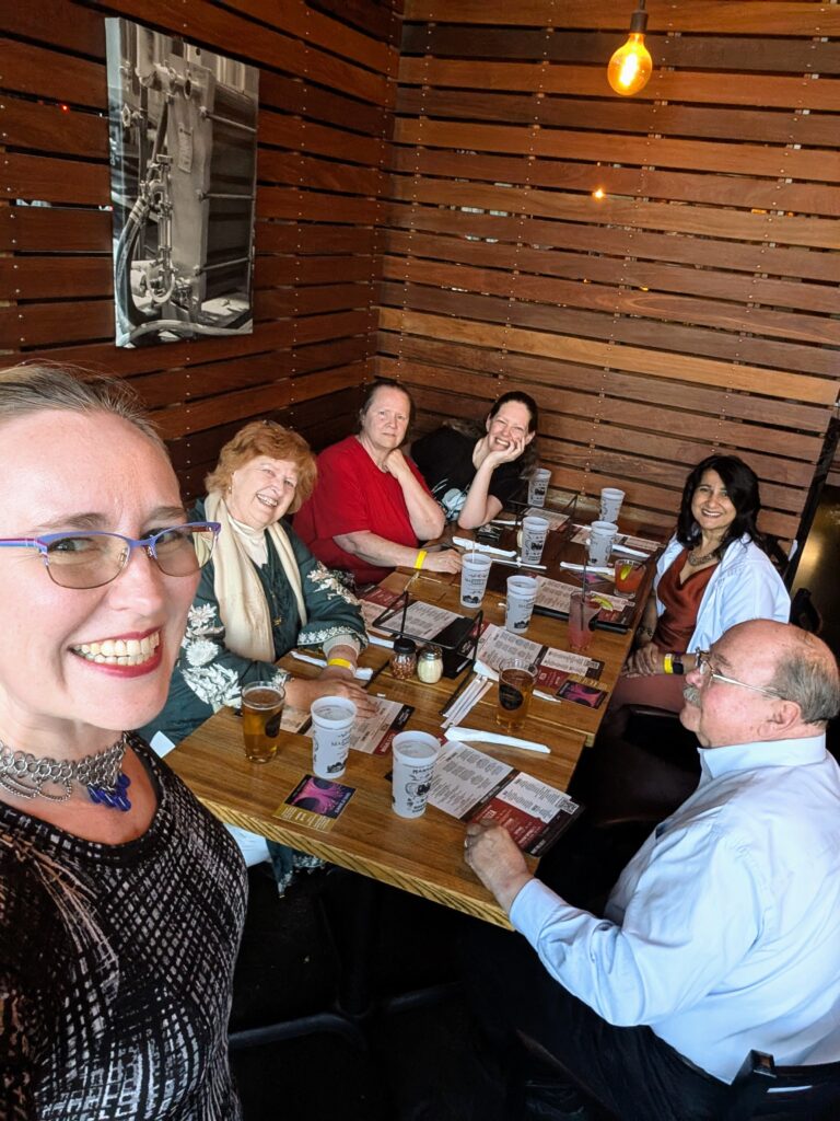 A group of 6 people sitting at a table at Martin City Brewery. Lindsay is in the foreground taking the selfie.