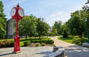 Bloomington, Indiana a red freestanding clock with a park with green trees and a walking path
